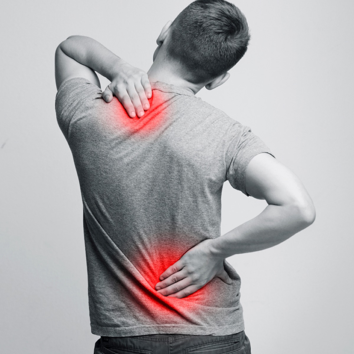 Person holding their neck and lower back in pain